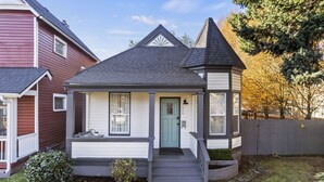 Et toetagers hus med en veranda, en grøn dør og en stensti, der fører til indgangen.