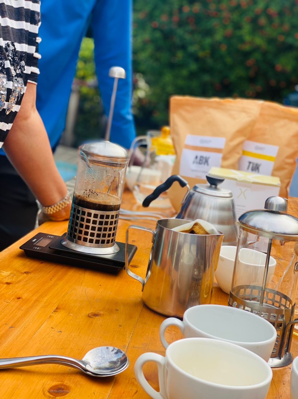 Een tafel met een koffiezetapparaat, een mok, een lepel en een glas.