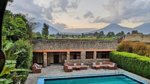 A pool area with a stone wall and seating, surrounded by greenery and a mountain view. - Tiloreza Volcanoes Ecolodge (Cyuve)