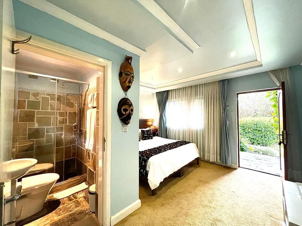 Un dormitorio con una cama grande, un baño con ducha y vistas al exterior.