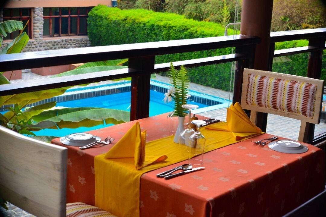 A dining table set with yellow napkins, silverware, and a menu board, overlooking a swimming pool and lush greenery.