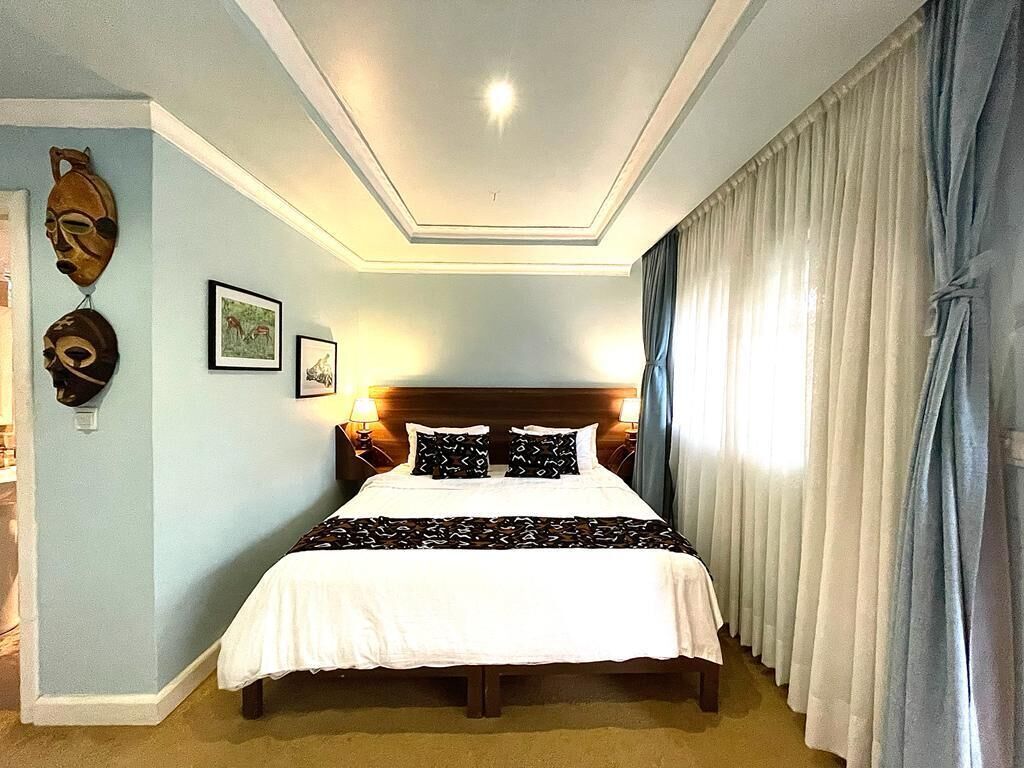 Een slaapkamer met een groot bed, een houten hoofdeinde en twee wandlampen.