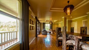 A spacious hallway with wooden flooring, a dining area with rustic wooden tables and chairs, and a sofa in the background. - Tiloreza Volcanoes Ecolodge (Cyuve)