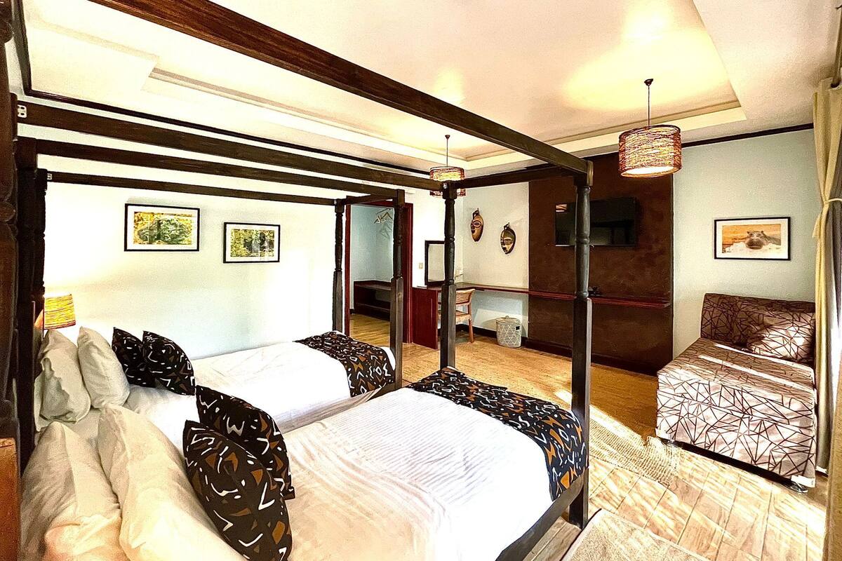 Una habitación de hotel con una cama grande, una cama más pequeña, un espejo y un sofá.