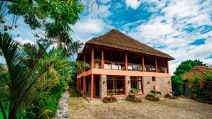 A two-story building with a thatched roof, surrounded by lush greenery and a cobblestone courtyard. - Tiloreza Volcanoes Ecolodge (Cyuve)