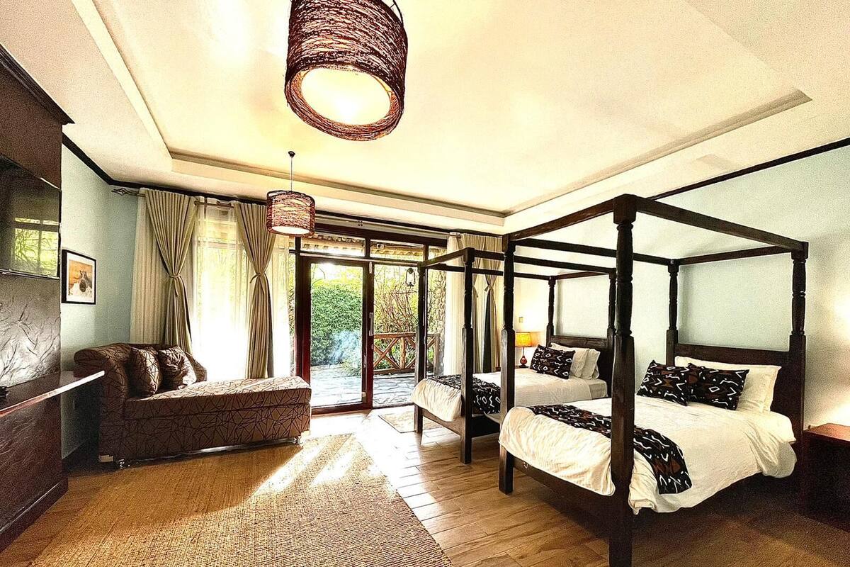Una cama con dosel, un sofá y un amplio ventanal con cortinas.