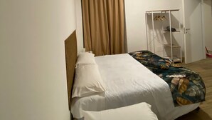 Ein Schlafzimmer mit einem Bett, einem Kleiderschrank und einem Fenster mit Vorhängen.
