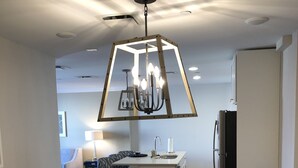 A modern dining area with a black table, beige chairs, and a unique geometric chandelier.