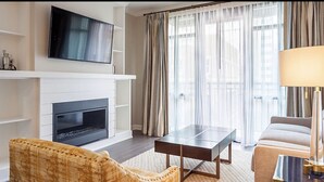 A modern living room with a flat-screen TV mounted above a fireplace, a sofa, a coffee table, and a lamp.