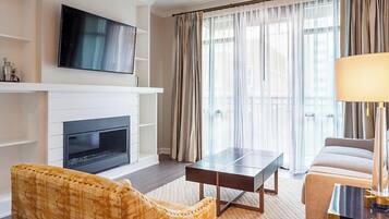 A modern living room with a flat-screen TV mounted above a fireplace, a sofa, a coffee table, and a lamp.