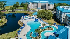 Un complex turístic amb una gran piscina central, diverses habitacions i vista a un llac.