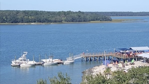 Un port esportiu amb diverses embarcacions amarrades, un moll que s'endinsa a l'aigua, i una zona coberta amb seients.