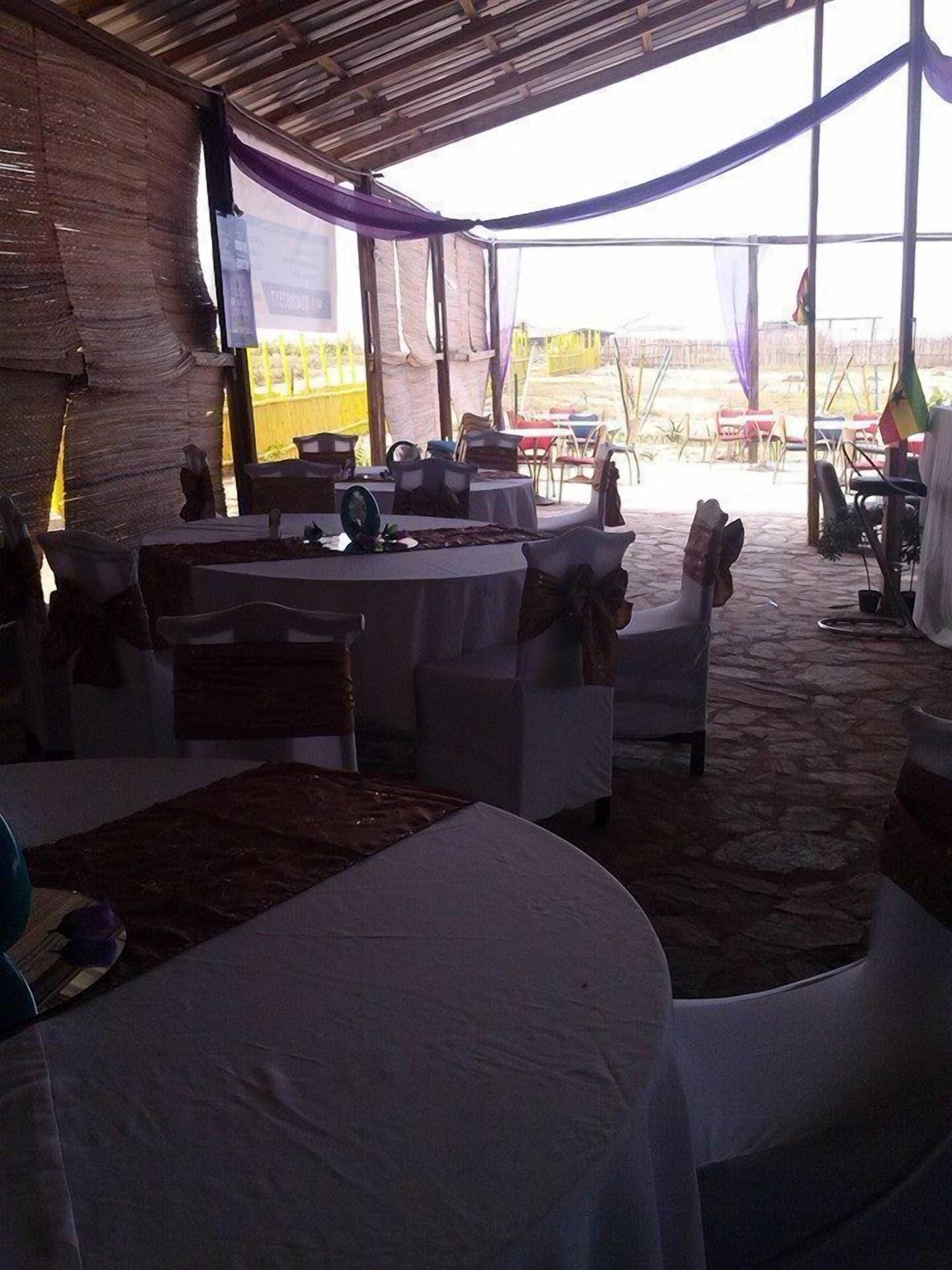 Un espacio para eventos al aire libre con mesas y sillas, cubierto por un techo.