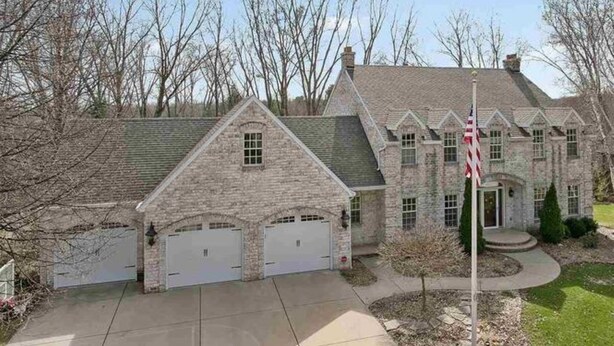 A stone house with a garage, a flag, and a well-maintained lawn. - Lambeau Field retreat 1.6 Miles from Lambeau 
2k sqft Lower level Luxury Walkout (Green Bay)