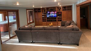 A living room with a sectional sofa, wooden shelving, a flat-screen TV, and a fireplace. - Lambeau Field retreat 1.6 Miles from Lambeau 
2k sqft Lower level Luxury Walkout (Green Bay)