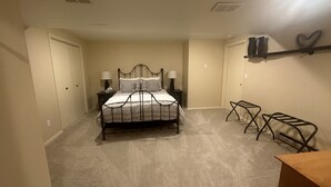 A bedroom with a bed, two bedside tables, a nightstand, a chair, a shelf with heart-shaped decorations, and a door. - Lambeau Field retreat 1.6 Miles from Lambeau 
2k sqft Lower level Luxury Walkout (Green Bay)