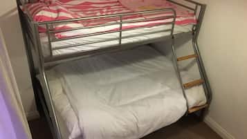 A bunk bed with a ladder, a pink and white striped blanket, and a lamp on the top bunk.
