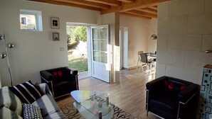 A spacious living area with a wooden ceiling, a glass coffee table, a sofa, and a dining table with chairs. - Gite des 3 Provinces (COUFFY)