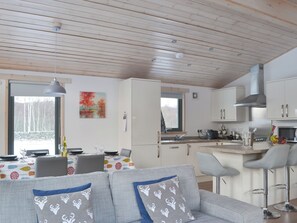 A modern kitchen with white cabinets, a stainless steel range hood, and a dining area with a table set for two.