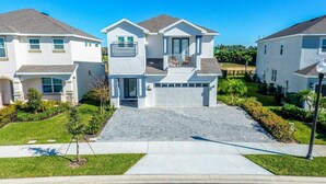 Een modern huis met twee verdiepingen, een oprit, en verzorgde gazons, onder een helderblauwe lucht.
