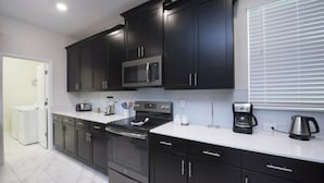 A modern kitchen with dark cabinets, stainless steel appliances, and a white countertop.