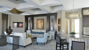 A modern living room with a white sofa, a coffee table, and a dining area with a bar. - Fabulous Single Home w/ Pool at Solterra Resort (Davenport)