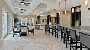 A spacious indoor area with a bar, seating, and ceiling fans. - Fabulous Single Home w/ Pool at Solterra Resort (Davenport)