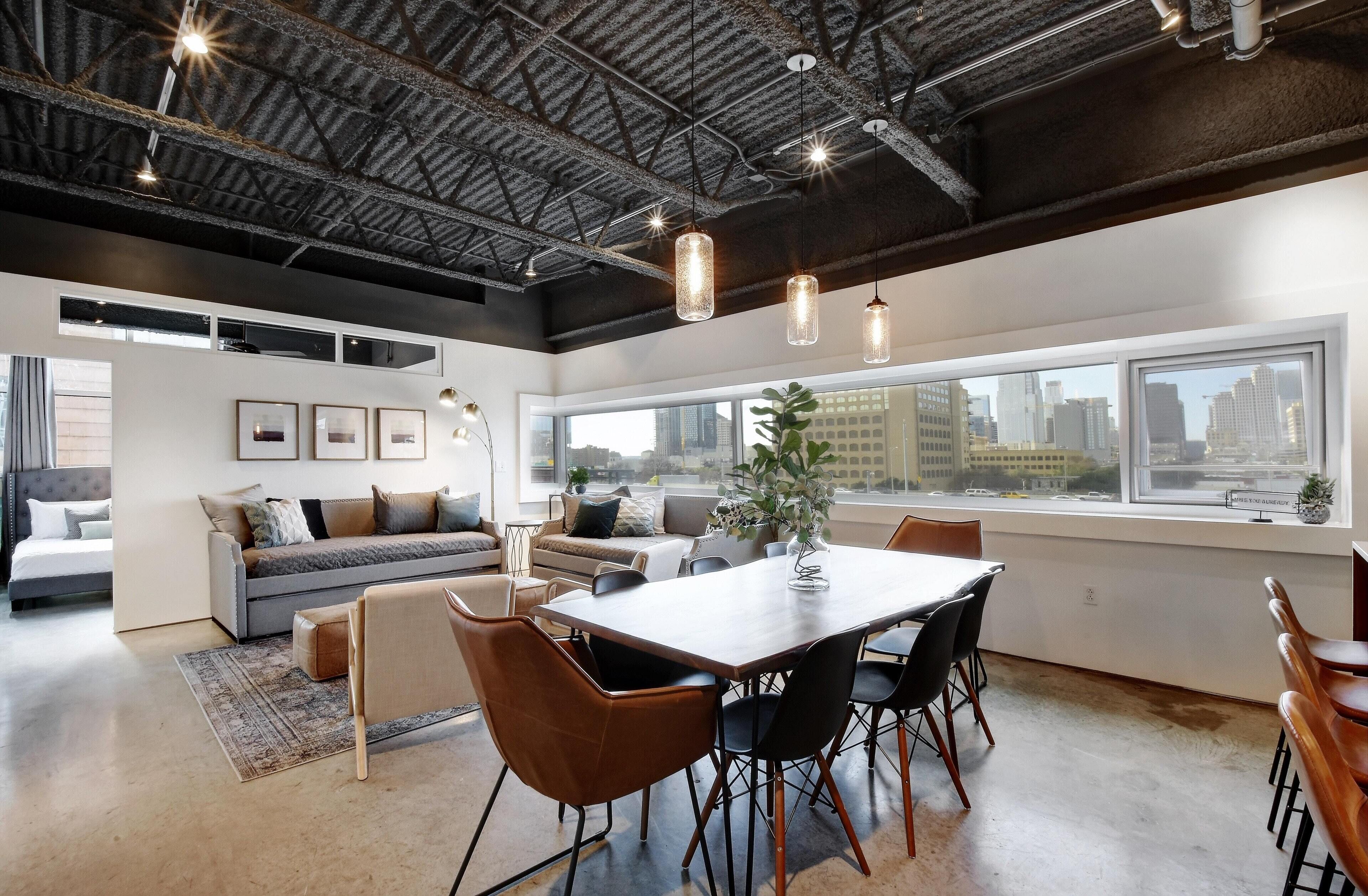 Ein modernes Wohnzimmer mit Essbereich, großen Fenstern und Blick auf die Stadt.