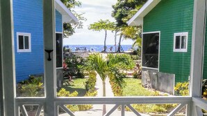 Blick durch ein Fenster auf ein Haus mit kleinem Garten und Meerblick.