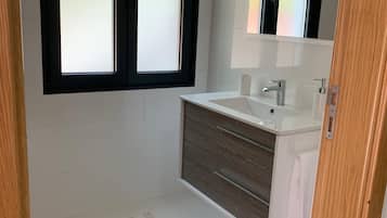 Un baño con un lavamanos blanco, un espejo y un felpudo a rayas en el suelo.