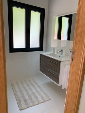 A bathroom with a white sink, a mirror, and a striped rug on the floor.