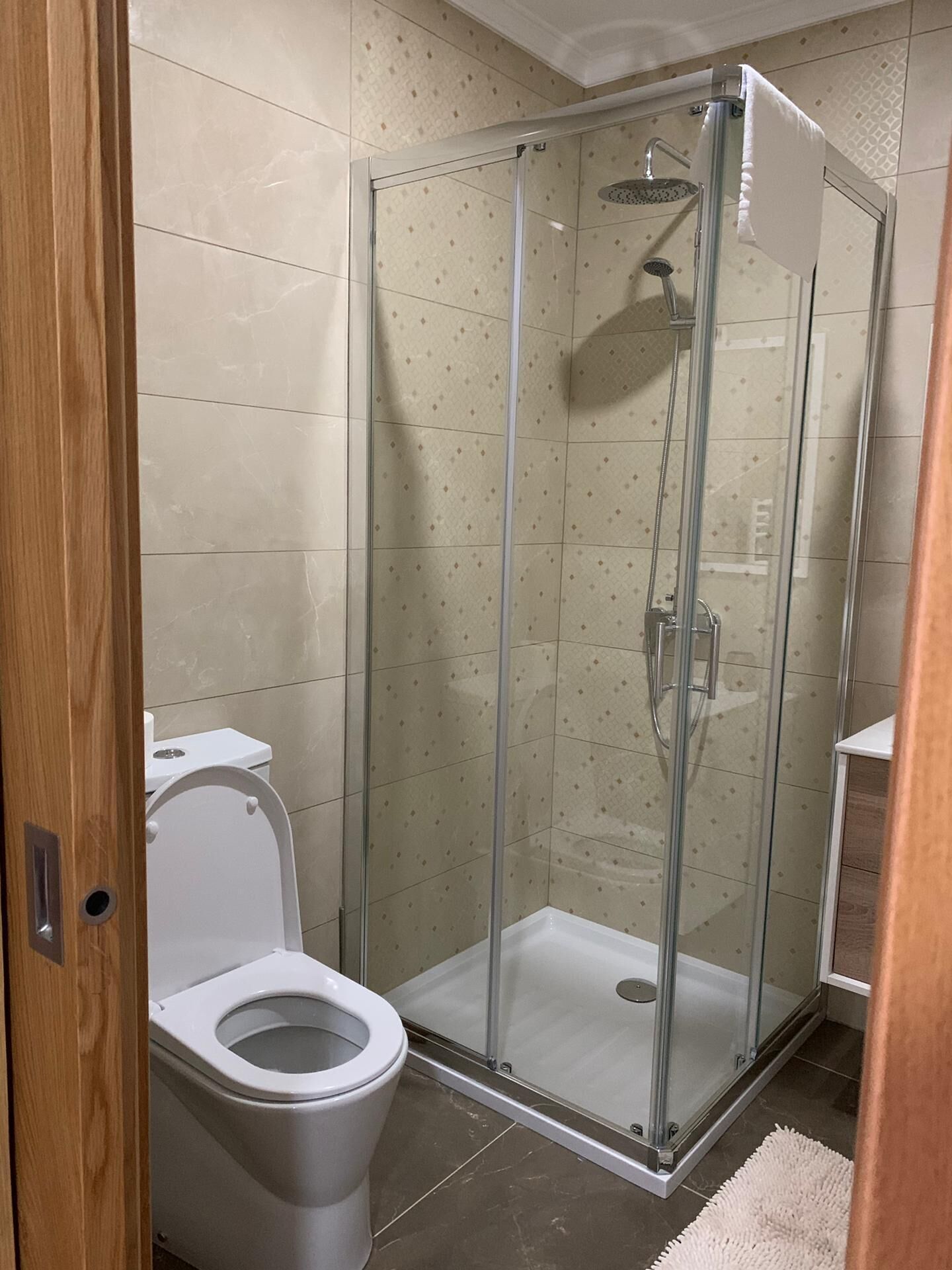 A bathroom with a glass-enclosed shower, a toilet, and tiled walls.