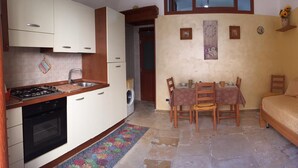 A compact kitchen with a stove, sink, and washing machine, a dining table with chairs, and a sofa. - Stay in the heart of the historic center of Bari (Bari)