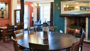 Un coin repas avec une table ronde, des chaises, un lustre et une cheminée.