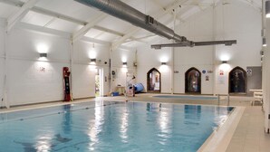 Une piscine intérieure avec des couloirs de nage clairement délimités, un poste de surveillance pour le sauveteur et un panneau indiquant que la piscine est fermée.