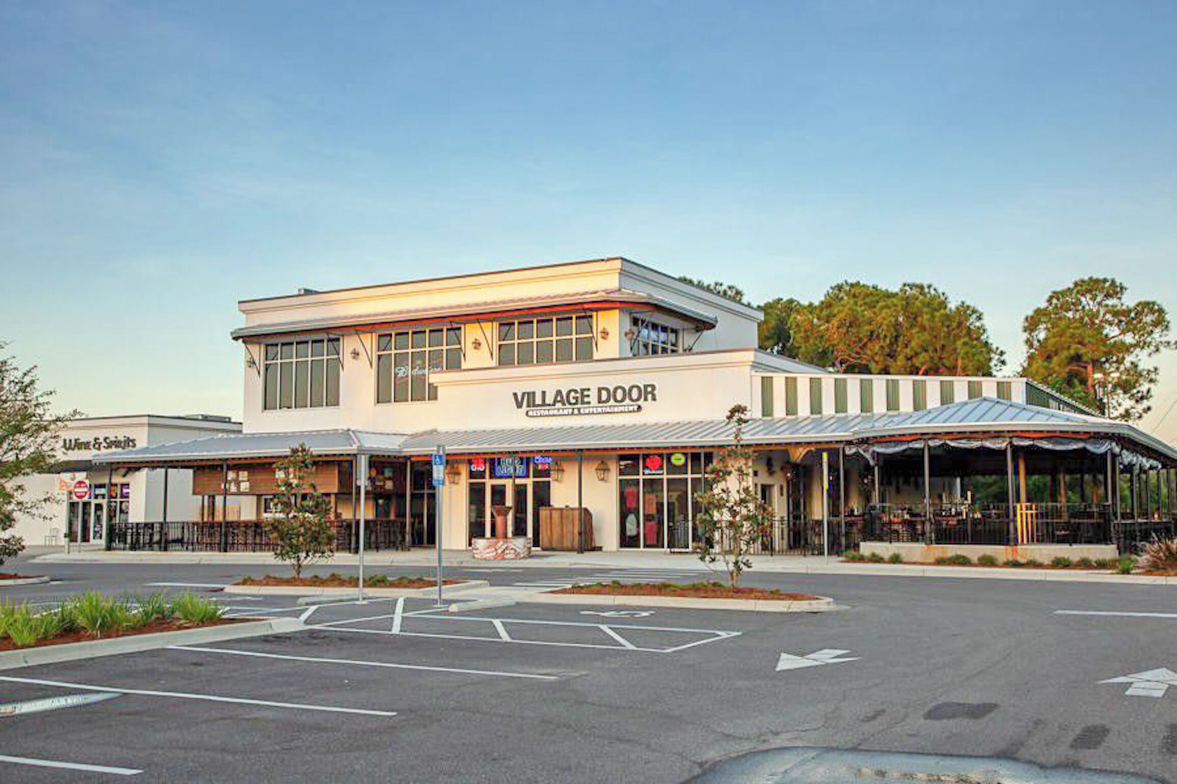 A two-story building with a sign reading "VILLAGE DOOR" and a covered outdoor seating area.