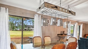 A dining area with a glass table, wicker chairs, and a hanging light fixture. - Seascape Amenities☀️Multiple Community Pools☀️Walk to Beach-Casa Bellal⛱️ (Miramar Beach)
