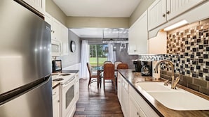A kitchen with a stainless steel refrigerator, a microwave, a stove, a sink with a modern faucet, and a dining area with chairs and a table. - Seascape Amenities☀️Multiple Community Pools☀️Walk to Beach-Casa Bellal⛱️ (Miramar Beach)