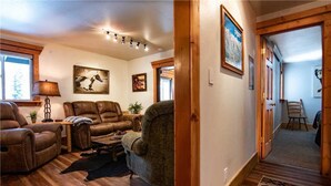 A cozy living room with leather sofas, a coffee table, and a rug. There are framed pictures on the wall and a lamp on a side table. - RMR: Tensleep A5 Condo in Teton Village (Teton Village)