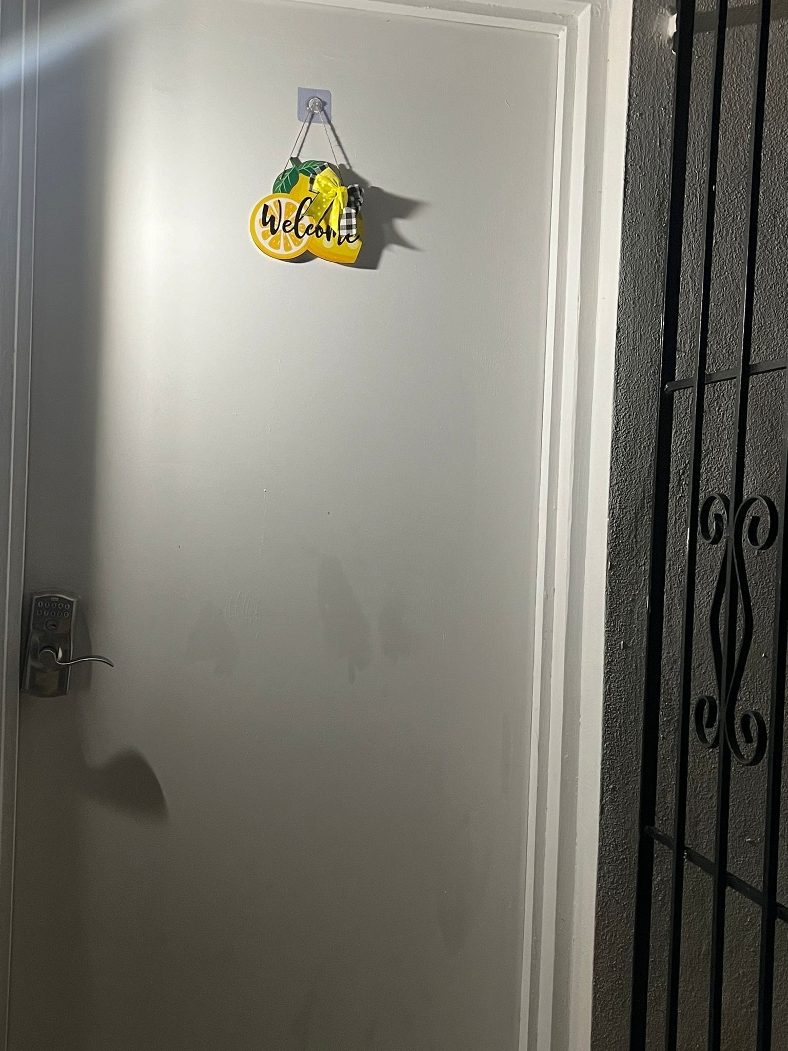 Una puerta blanca con un letrero de 'Welcome' y un teclado de cierre.