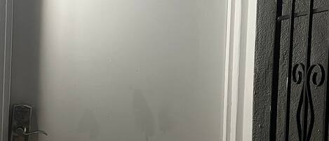 Una puerta blanca con un letrero de 'Welcome' y un teclado de cierre.
