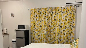 Un dormitorio con cama, microondas, refrigerador y baño.