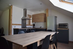 A modern kitchen with a dining area, featuring a wooden table, chairs, a stove, and a microwave.