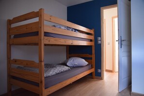 A bunk bed in a room with blue walls and a wooden floor.