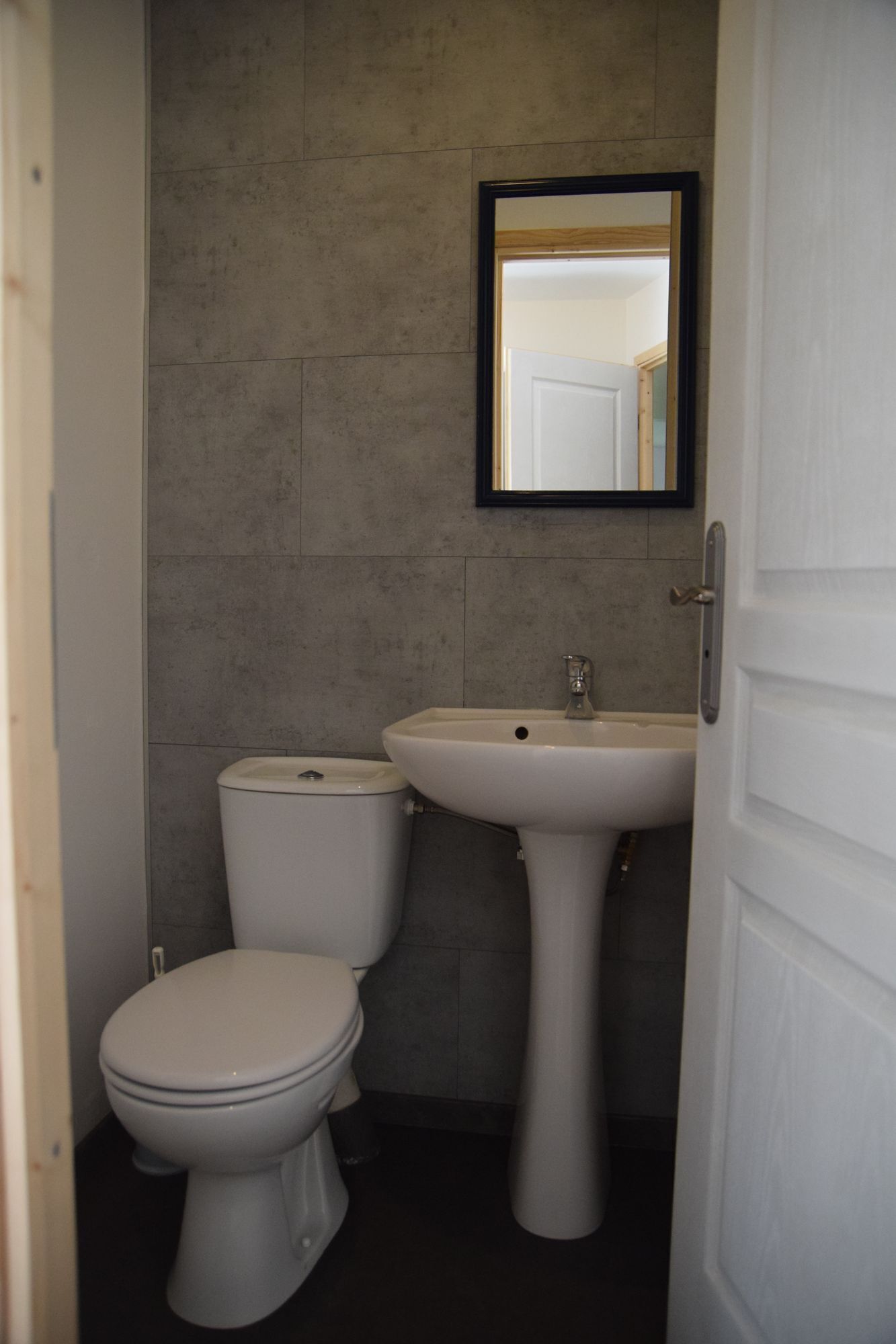 A small bathroom with a toilet and a pedestal sink.