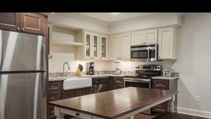 A modern kitchen with stainless steel appliances, white cabinetry, and a central island.