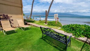 Eine Terrasse mit zwei Holzliegen, einer Metallbank und Blick aufs Meer.