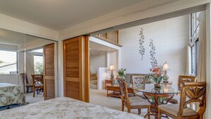 Ein Hotelzimmer mit einem Bett, einem Esstisch mit Stühlen, einer Treppe und einer Wand mit Dekorationselementen.