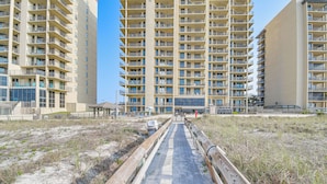 A high-rise residential building with multiple balconies and a sandy pathway leading to the entrance. - Gulf Coast Luxury Getaway on Orange Beach w/ Views (Orange Beach)