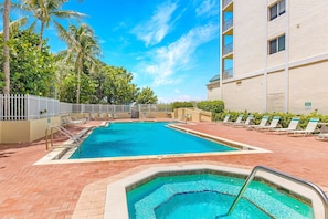 A swimming pool with a 'No Diving' sign, surrounded by lounge chairs and palm trees.